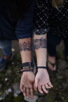 two people holding hands with tattoos on them