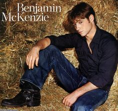 a young man sitting on top of a pile of hay