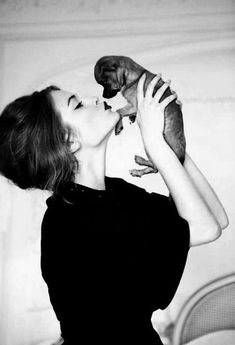 a black and white photo of a woman holding a small dog in her arms,