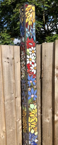 a tall metal pole with colorful flowers painted on it's side next to a fence