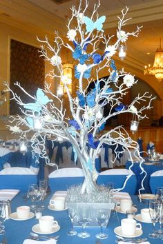 the centerpieces are decorated with blue and white flowers, leaves, and branches