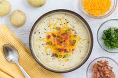 a bowl of potato soup with bacon, cheese and green onions next to other ingredients