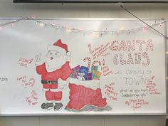 a white board with writing on it that says merry christmas and santa clause holding presents