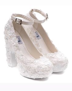 a pair of white high heeled shoes with flowers on them