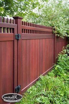 a red wooden fence surrounded by green plants