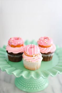 three cupcakes with pink frosting and sprinkles on a green plate