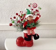 an elf figurine sitting on top of a red boot with candy canes