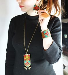 a woman in black shirt holding up two necklaces and matching bracelets on her wrist