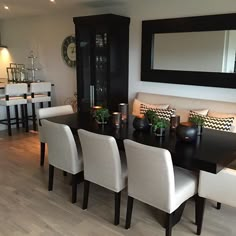 a dining room table with white chairs and candles on the centerpiece in front of it