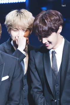 two young men in suits and ties looking at each other's faces while standing next to each other