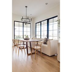 a living room filled with furniture next to large windows and a chandelier hanging from the ceiling