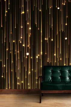 a green couch sitting in front of a wall with lights on it