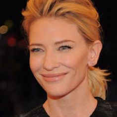 a woman with blonde hair and blue eyes smiles at the camera while wearing a black dress