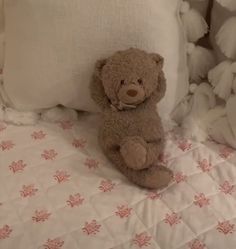 a brown teddy bear sitting on top of a bed