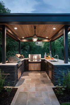 an outdoor kitchen with grill and sink under a covered gazebo at dusk or dawn