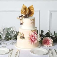 there is a wedding cake on the table with flowers and silverware in front of it