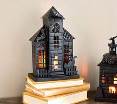 two halloween decorations sitting on top of books next to each other and lit candles in front of them