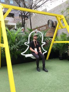 a man is sitting on a swing in the grass