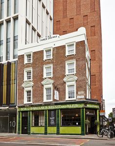 an old brick building on the corner of a street in front of a tall building