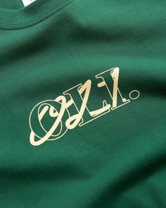 a green t - shirt with white lettering on the front and bottom that says fzc