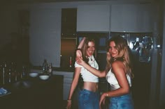 two young women standing in a kitchen next to each other