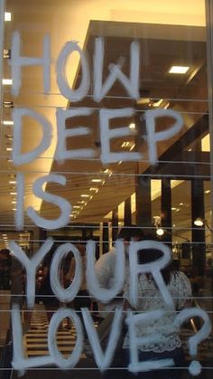 the words how deep is your love? written in a window with white spray paint