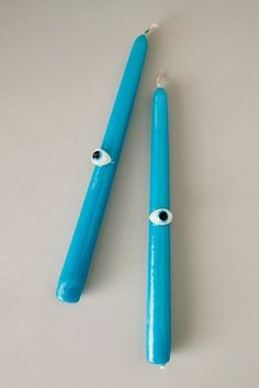 two blue toothbrushes sitting next to each other on a white counter top with an eye drawn on them