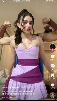 a woman in a purple dress flexing her muscles and looking at the camera screen