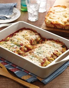 a casserole dish with meat and cheese in it sitting on a table next to two forks