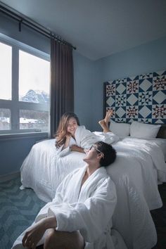 two people laying on a bed in a room with blue walls and patterned headboards