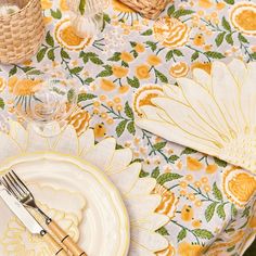 the table is set with yellow and white plates, napkins, and silverware