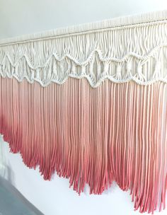 pink and white wall hanging with fringes on it