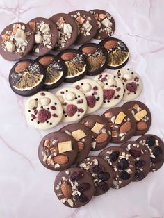 chocolate covered cookies with nuts and dried fruit arranged on a marble counter top for display