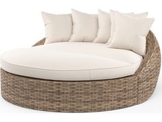 a wicker couch with white cushions and pillows on it's backrests