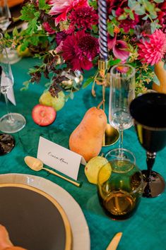 the table is set with flowers, fruit and wine glasses for an elegant dinner party