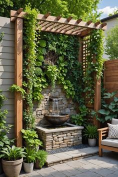 an outdoor fountain surrounded by greenery and potted plants on the side of a house