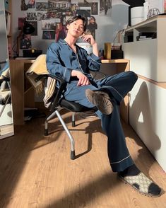 a woman sitting in an office chair with her feet on the desk and looking at the camera