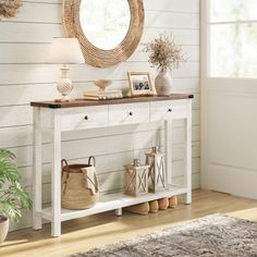 a white console table with two baskets on it and a round mirror hanging above it