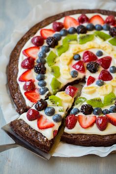 a fruit pizza is cut into slices on a white plate