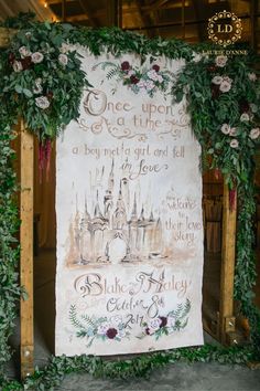 a wedding sign with flowers and greenery on the front is displayed in an indoor setting