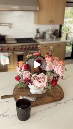 a kitchen counter with a wooden cutting board topped with flowers and a cup of coffee