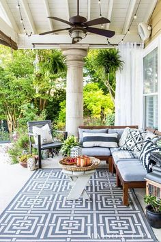 an outdoor living area with couches, tables and plants on the porch flooring