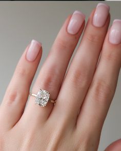 a woman's hand with a diamond ring on top of her finger and the other hand holding an engagement ring