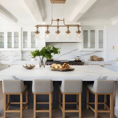 a large kitchen with marble counter tops and stools in front of the center island