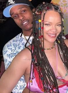 two people posing for the camera in front of a wall with many beads on it