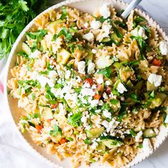 a white bowl filled with pasta salad and garnished with parmesan cheese