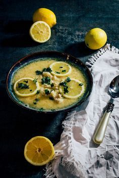 a bowl of soup with lemons on the side