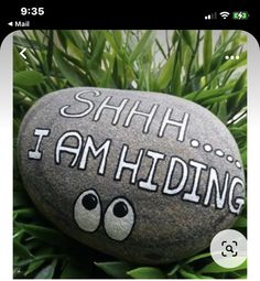 a rock with the words shh i am hiding painted on it sitting in some grass