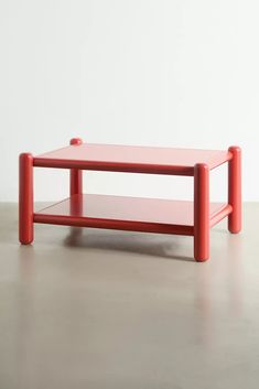 a red coffee table sitting on top of a cement floor next to a white wall