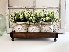 three mason jars with flowers in them are sitting on a wooden stand next to a glass vase